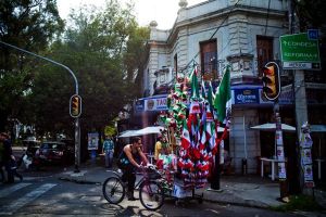 A traveler passes a cart selling Mexican flags in Mexico City’s La Roma neighborhood.