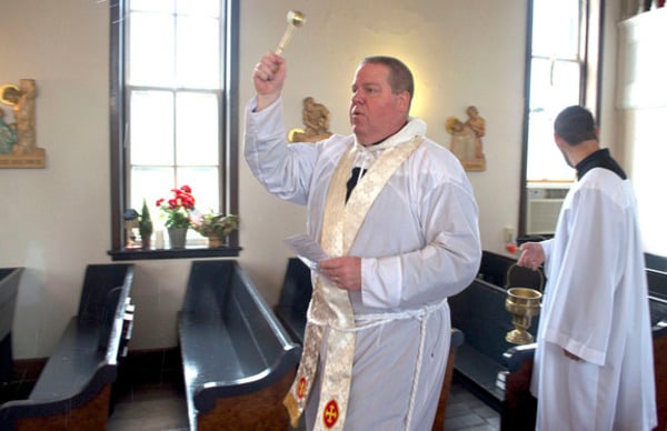 Father James Hamrick sprinkles holy water as he walks amid the pews at St. John the Baptist Orthodox Church. David Frey photo.