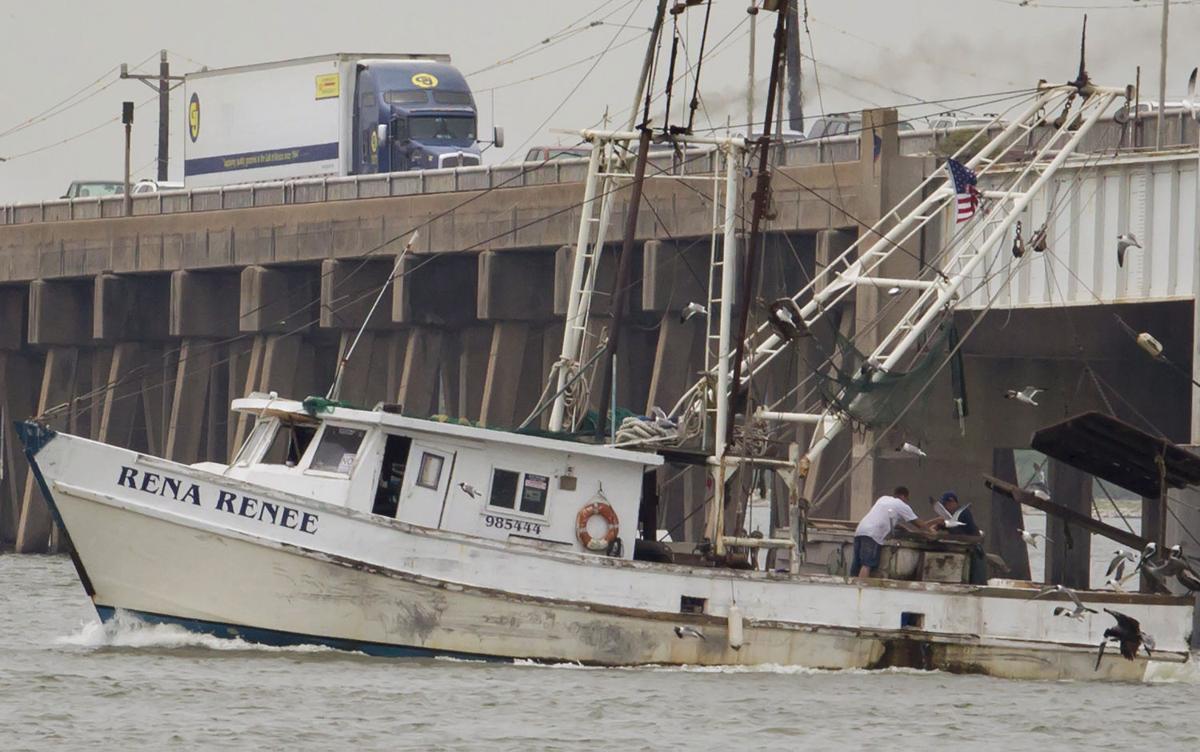 Traffic waits on the Pelican Island Causeway as a fishing boat crosses 