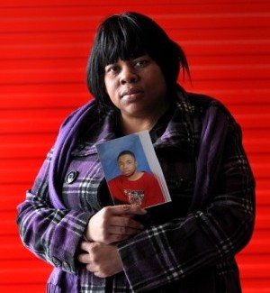 Felicia Vanderford holds a photo of her deceased son Dorcy Davis, eyes partially shut