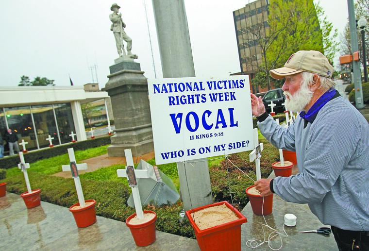Denny Kimbrell, of the local VOCAL chapter, secures a sign near memorial crosses at the Lauderdale County Courthouse in Florence after building the display for domestic violence victims. Jim Hannon/TimesDaily file