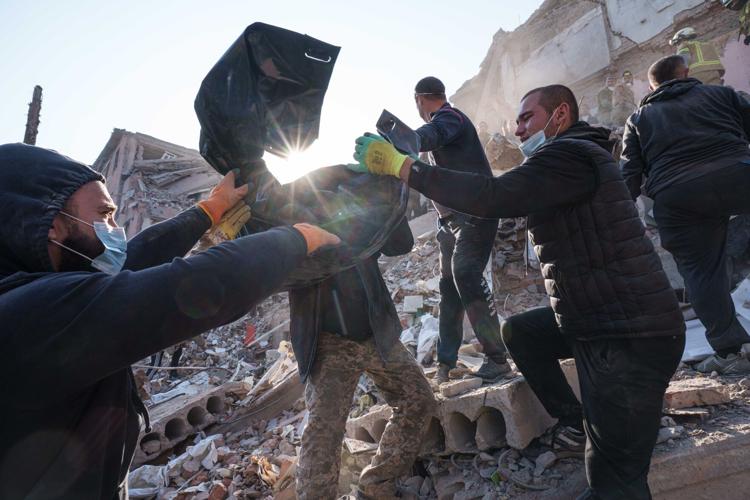 Locals and rescuers clear the rubble of a residential building destroyed in a Russian missile strike, in photos
