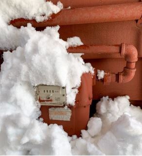 An image of a gas meter being cleared of snow to prevent a gas leak.