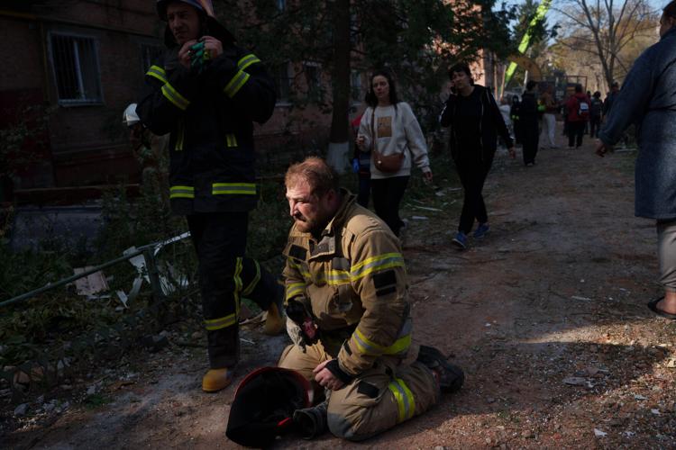 Locals and rescuers clear the rubble of a residential building destroyed in a Russian missile strike, in photos
