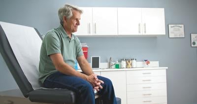 STOCK Senior male patient waiting patiently for doctor sitting on exam room table