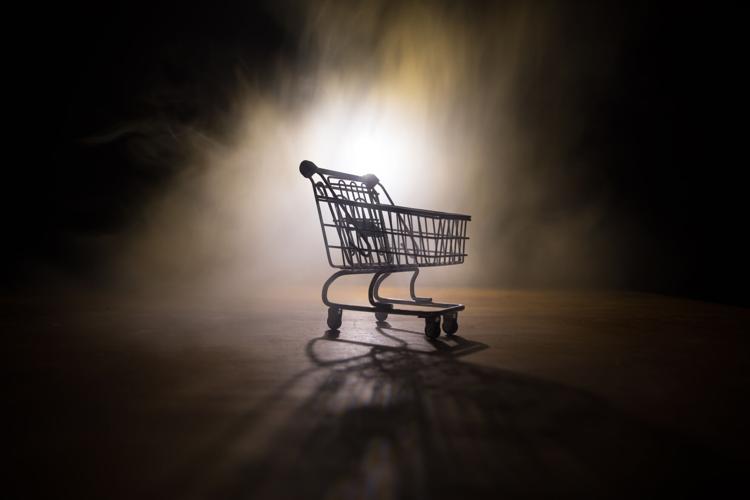 Empty shopping trolley on dark toned foggy background with some copy space. Financial crisis concept.