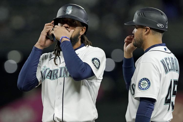 Seattle Mariners' J.P. Crawford, left, reacts after hitting a