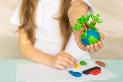 A small globe with trees in the hands of a child.