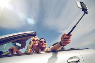 happy couple in car taking selfie with smartphone