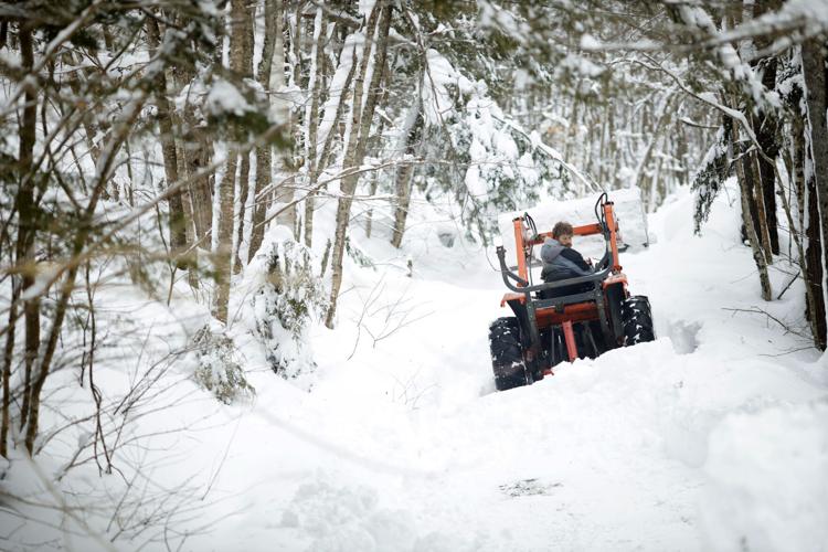 man looks behind him on a tractor in the snow