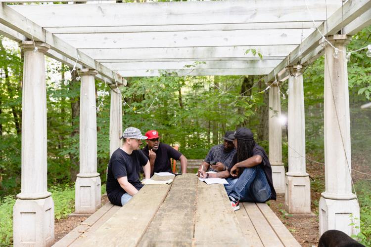 hip hop artists collaborate on songs around a table