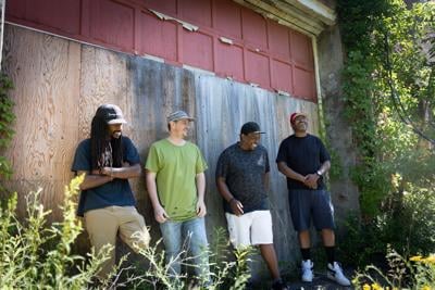 four hip hop artists lean against a wall