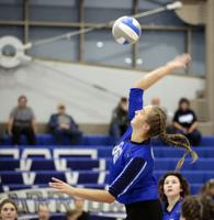 volleyball player in blue spikes ball