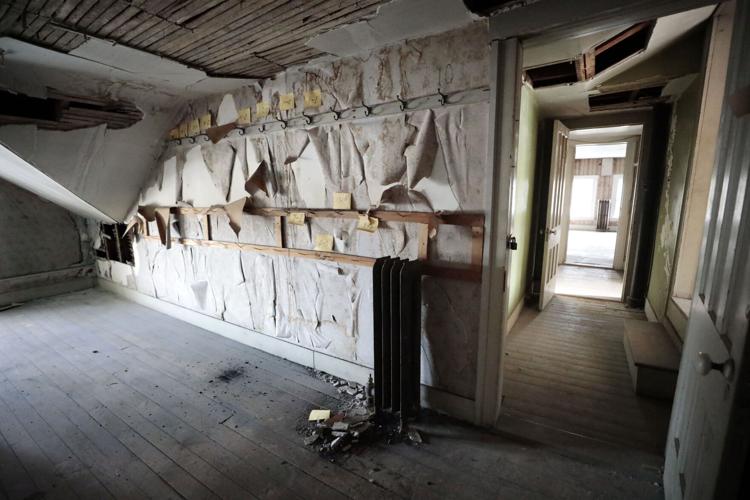 room with hooks in historic house with peeling wallpaper