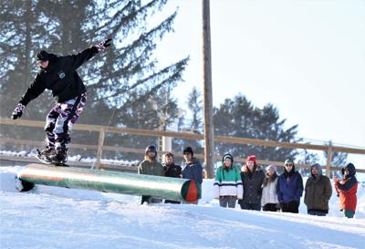 snowboarders ride rails at Bousquet