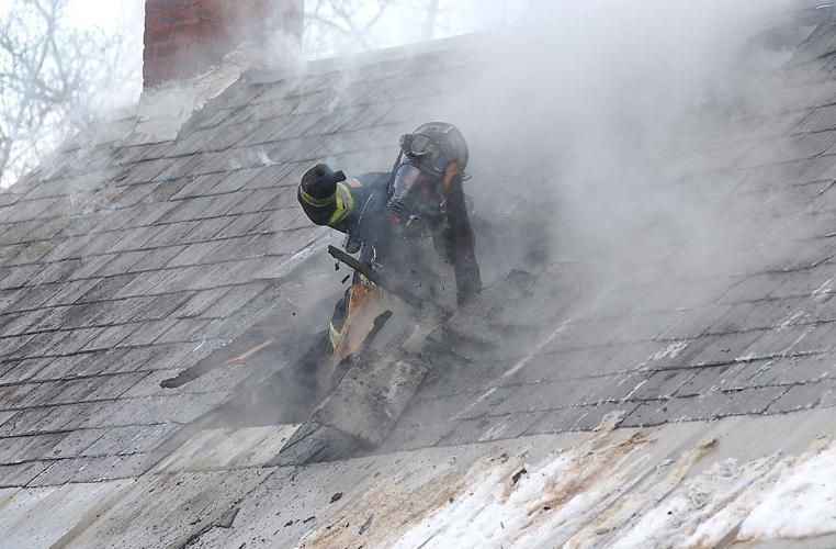 A firefighter breaks through a roof fighting a fire
