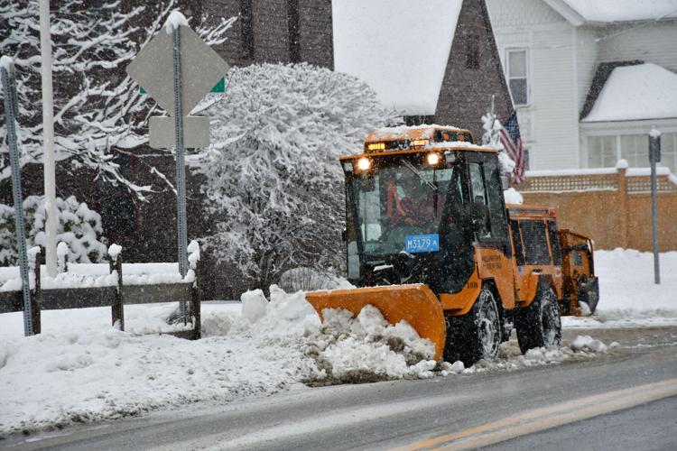 A plow clears the sidewalks of snow