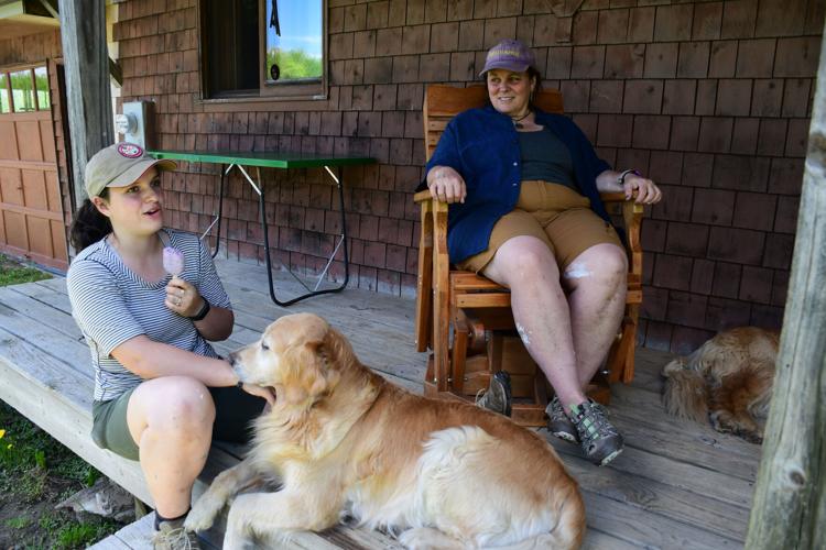 Two women sit on a porch with their dogs