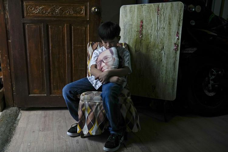 A boy holds a pillow with an image of his late father