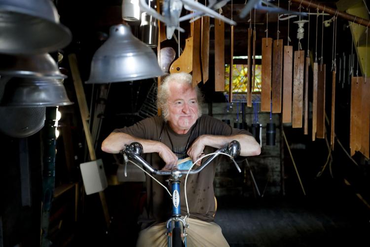 man sits on bike surrounded by instruments hanging from ceiling