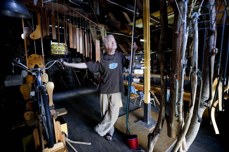 man stands in barn surrounded by invented instruments