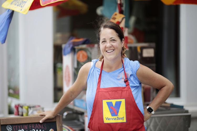 female hot dog cart owner smiling in front of stand