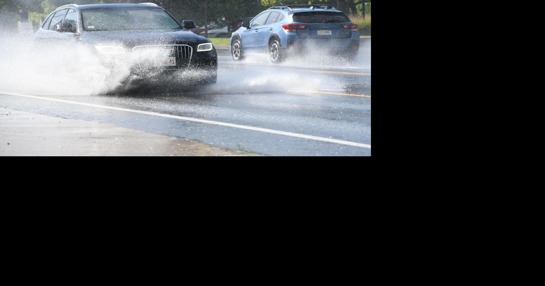 A couple of cars ride through a puddle