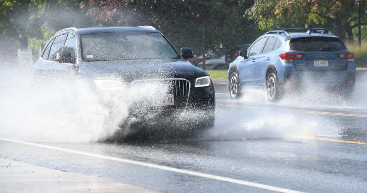 A couple of cars ride through a puddle