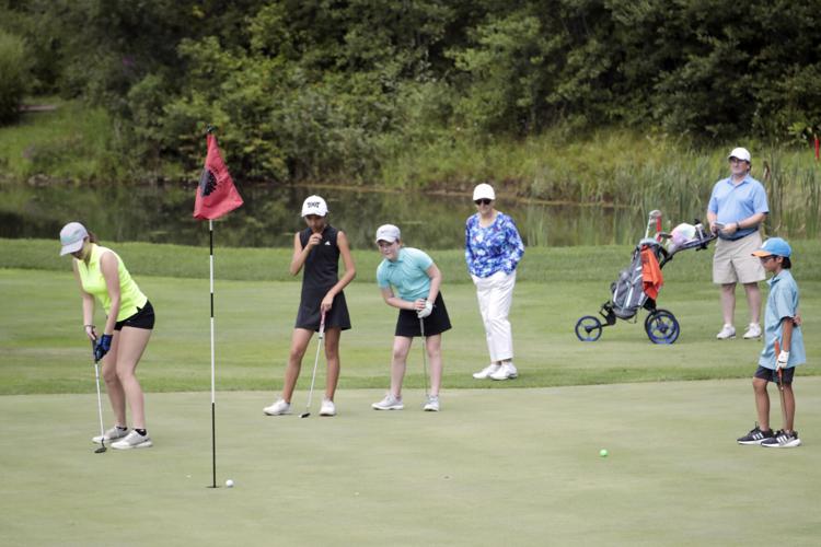 group of girls watch another girl putt golf ball