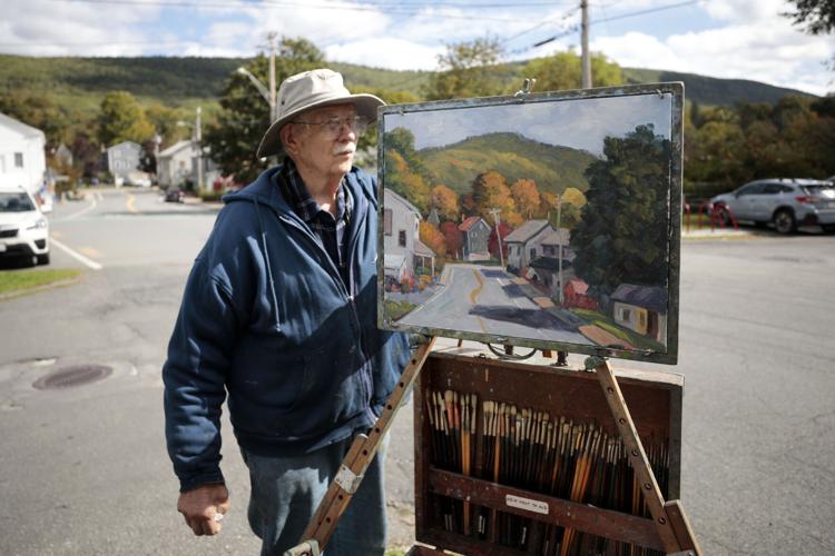 man packs painting and easel after painting town in fall