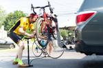 Male cyclist works on his bike secured in a hitch rack.