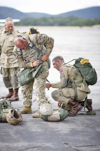 paratroopers help each other put on parachutes