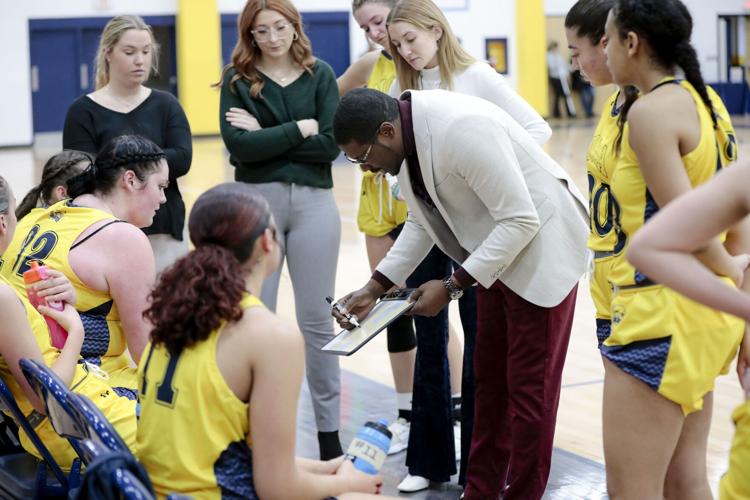 women's basketball coach talks to players with white board on bench