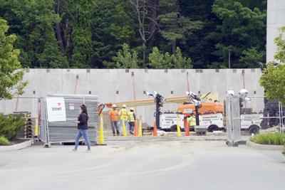 Construction workers outside next to large cement wall