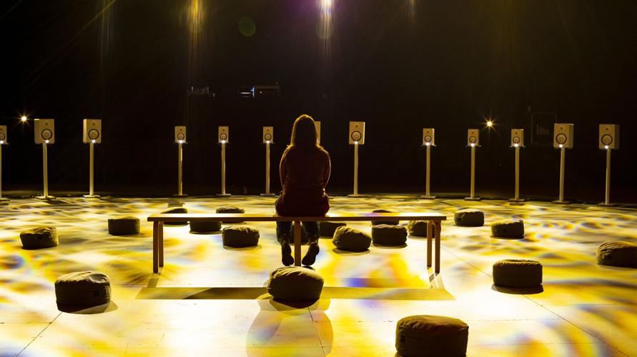 Person sits in the center of a circle of speakers.