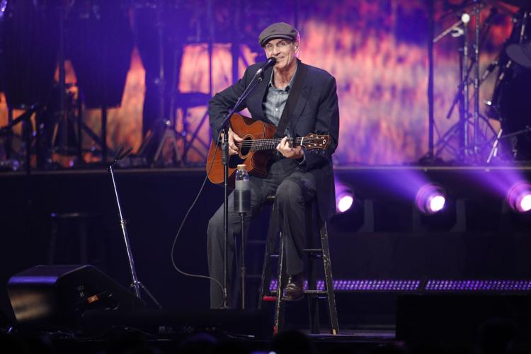 James Taylor plays the guitar on stage