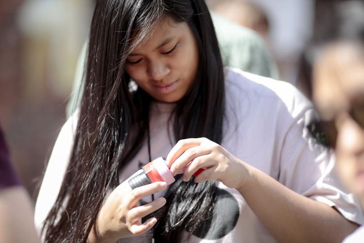 young woman tapes a balloon to a plastic fitting