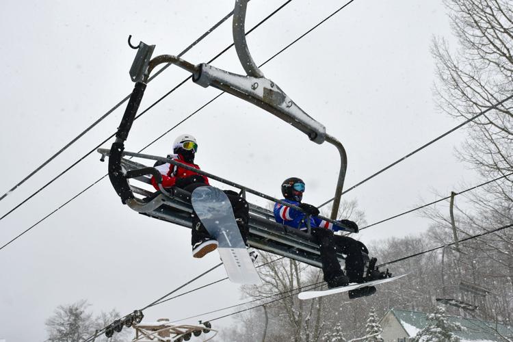 Snowboarders ride a ski lift