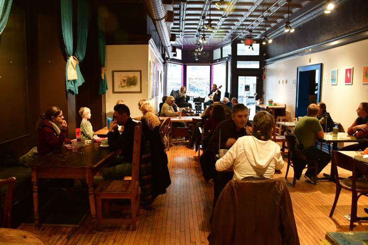 A man plays guitar while a woman sings in a cafe