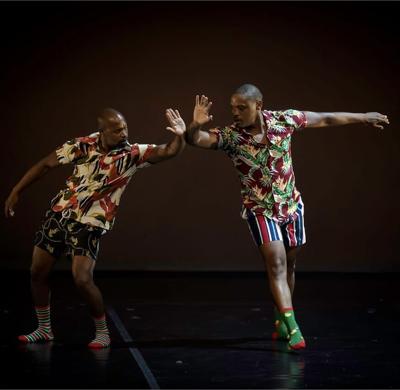 two men in matching outfits high-five during a dance