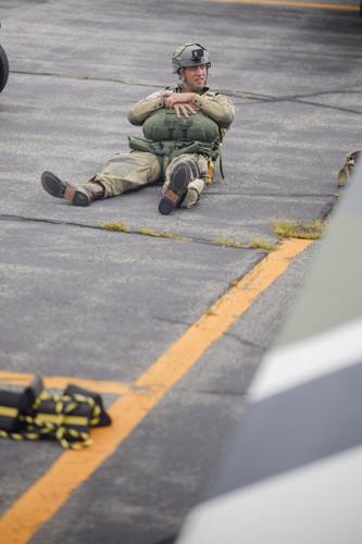paratrooper rests on tarmac laden with gear