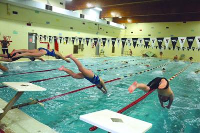 Swimmers jump into the pool