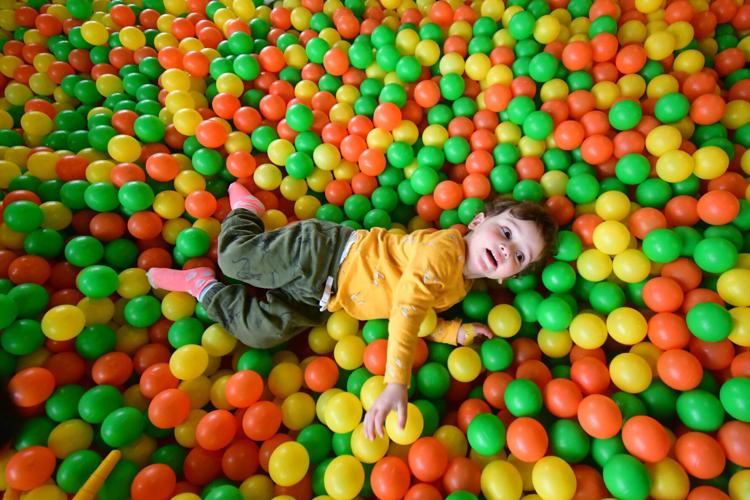 A child lays in the ball pit