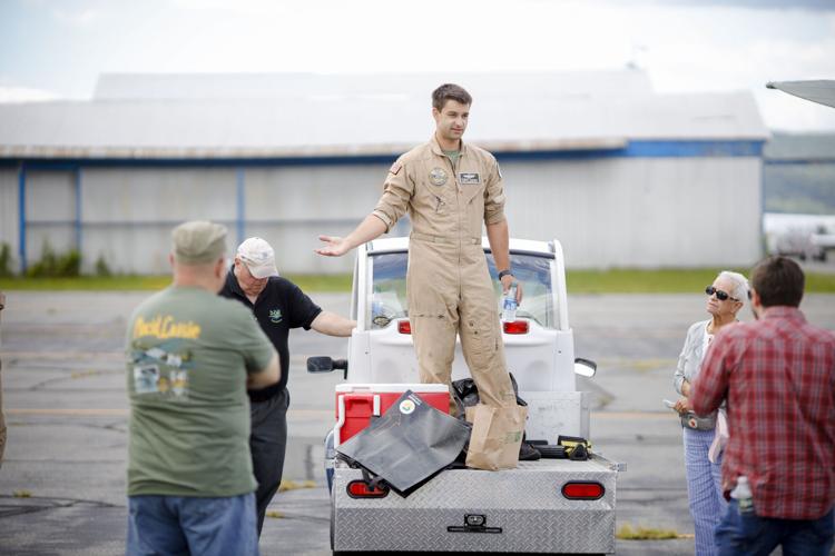 pilot in tan flight suit talks to group of people