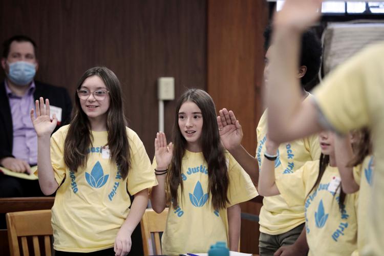 students hold up hands in courtroom in mock trial