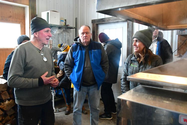 People chat in a sugarhouse as sap is boiling