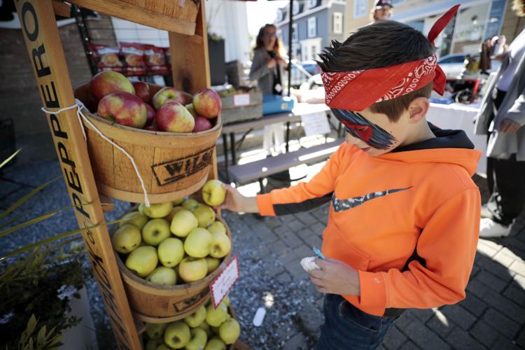 boy in orange sweatshirt picks apple from stand