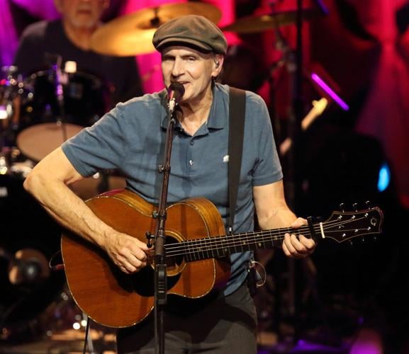 James Taylor holding guitar and singing