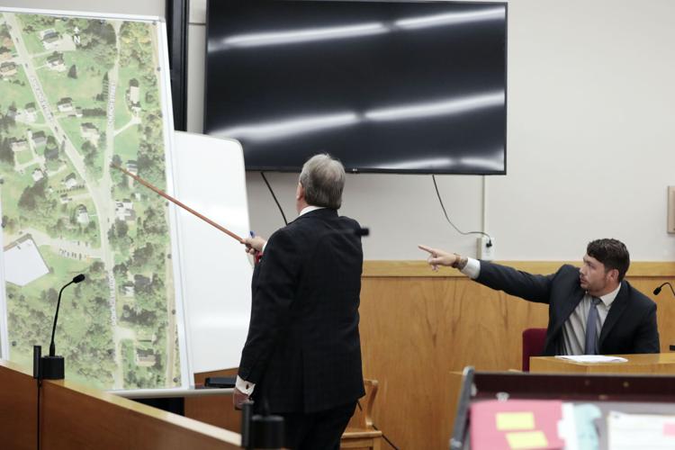 lawyer points with stick and witness points with finger at large map