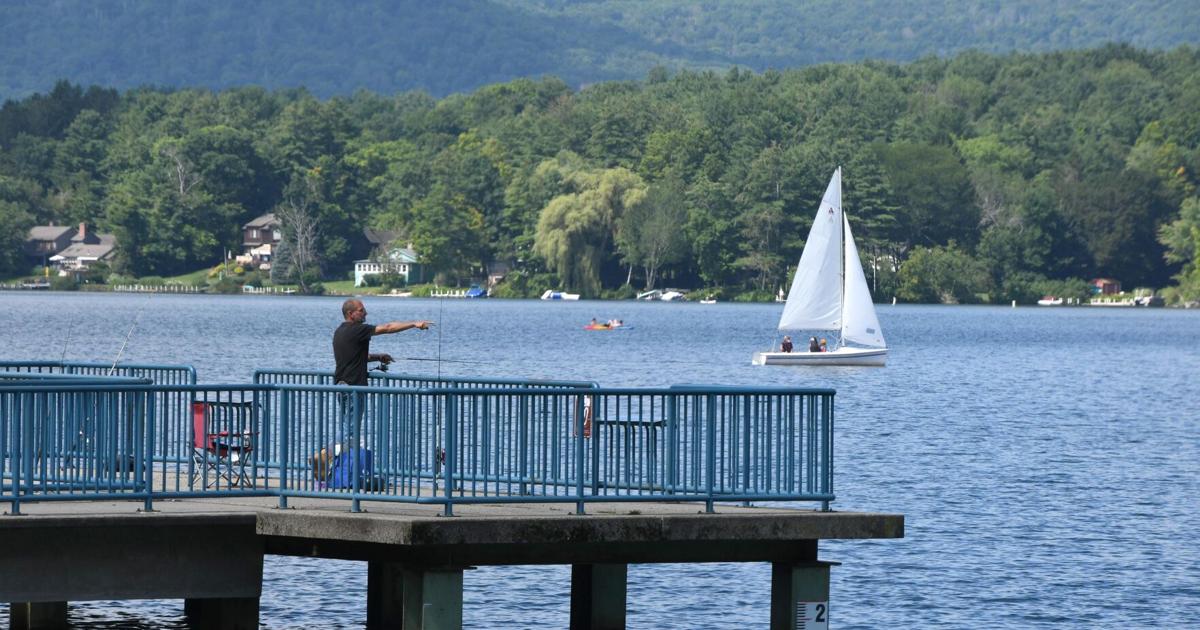 People fish and sail on a lake